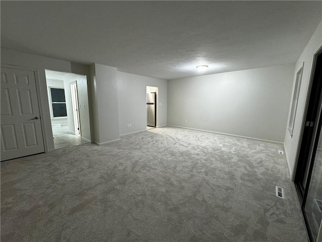 empty room featuring carpet floors, baseboards, visible vents, and a textured ceiling