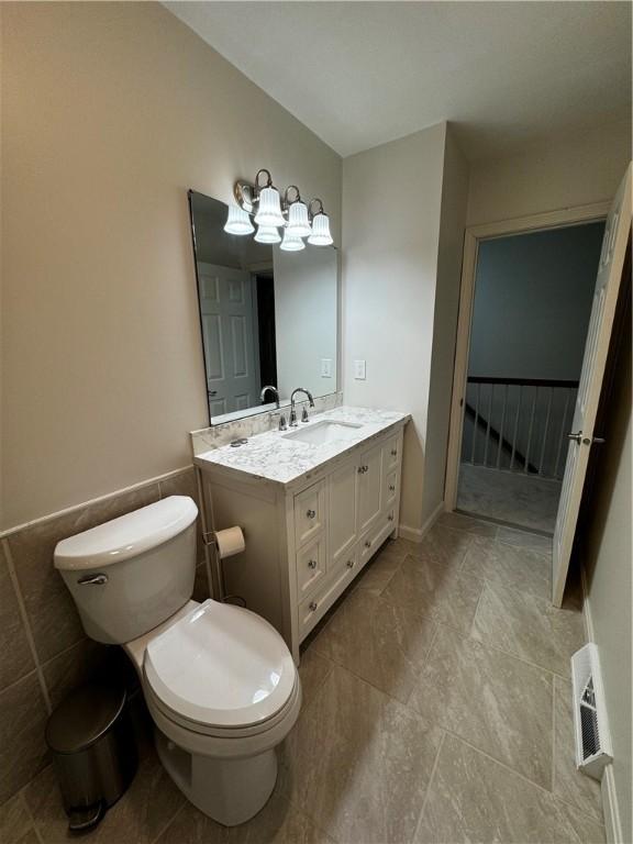 bathroom with toilet, visible vents, and vanity