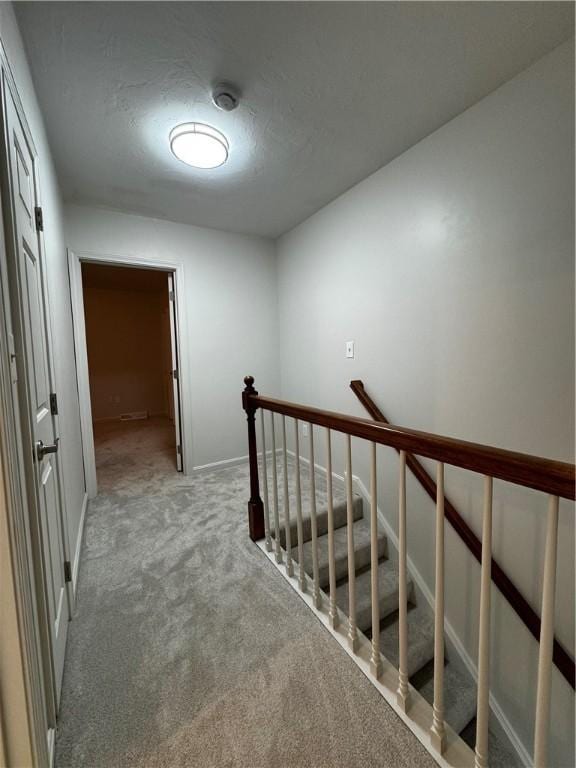 stairs with a textured ceiling and carpet flooring