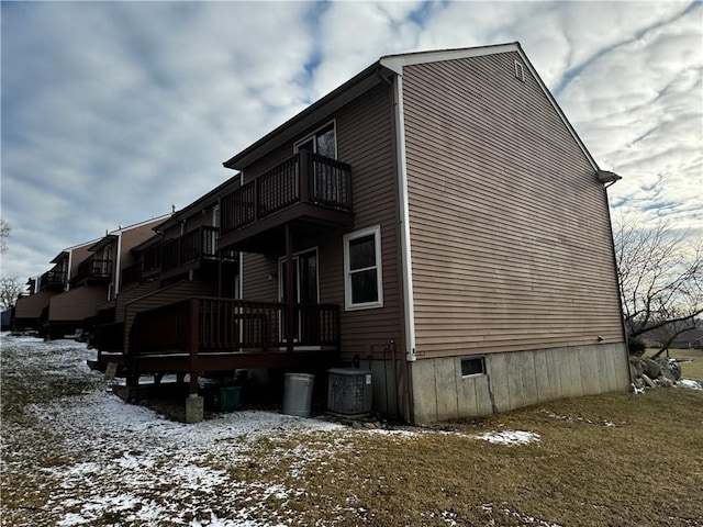 view of snow covered exterior with cooling unit and a balcony