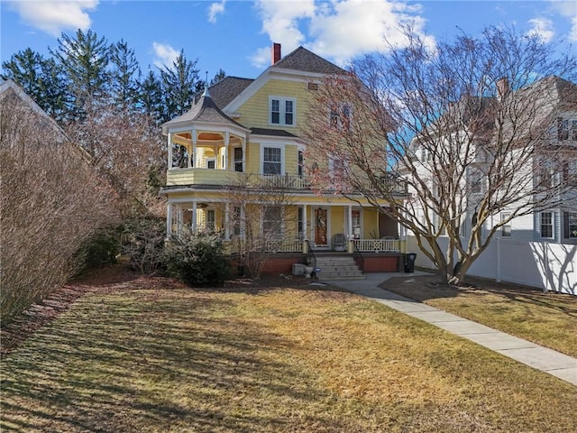 victorian house with roof with shingles, a porch, a front lawn, and fence