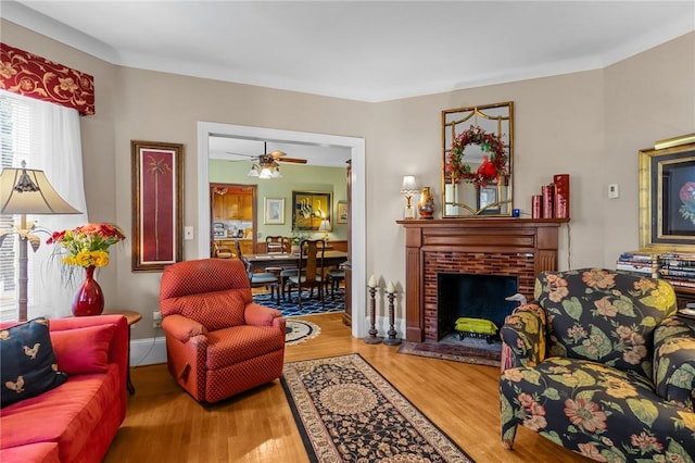 living room with a brick fireplace, wood finished floors, and baseboards