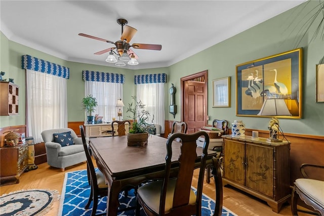 dining room featuring wainscoting, wood finished floors, and a ceiling fan