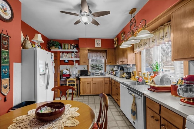 kitchen featuring white refrigerator with ice dispenser, ceiling fan, light countertops, stainless steel dishwasher, and a sink