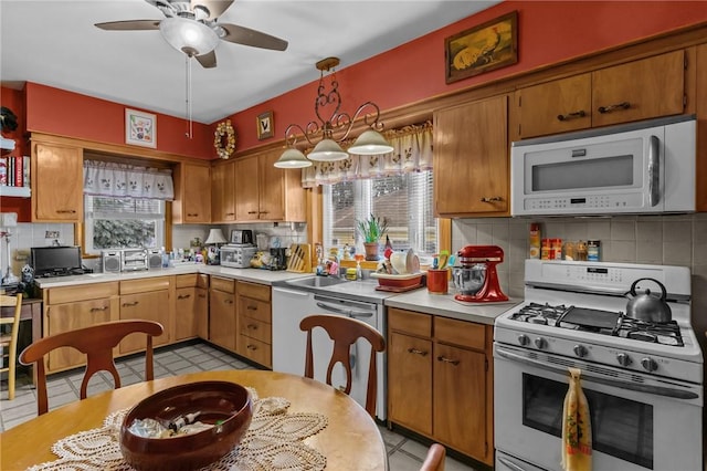 kitchen with light countertops, backsplash, a ceiling fan, brown cabinetry, and white appliances