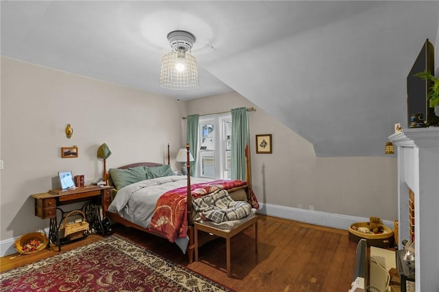 bedroom with vaulted ceiling, wood finished floors, and baseboards