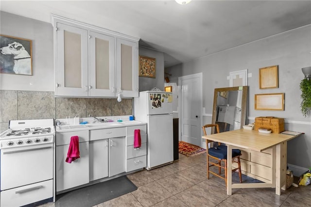 kitchen with white appliances, light tile patterned floors, decorative backsplash, light countertops, and a sink