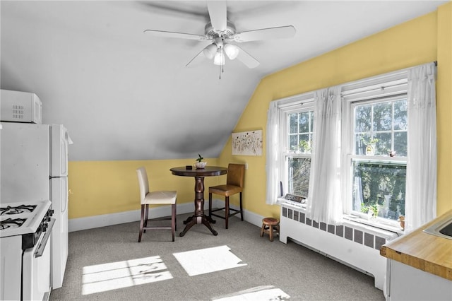 interior space with baseboards, a ceiling fan, radiator heating unit, vaulted ceiling, and carpet flooring