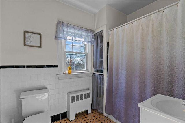 bathroom with toilet, a wainscoted wall, tile walls, tile patterned floors, and radiator heating unit