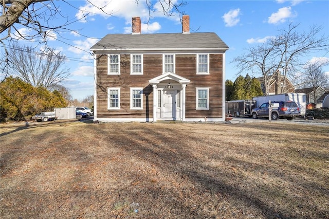 colonial home with a chimney and a front yard