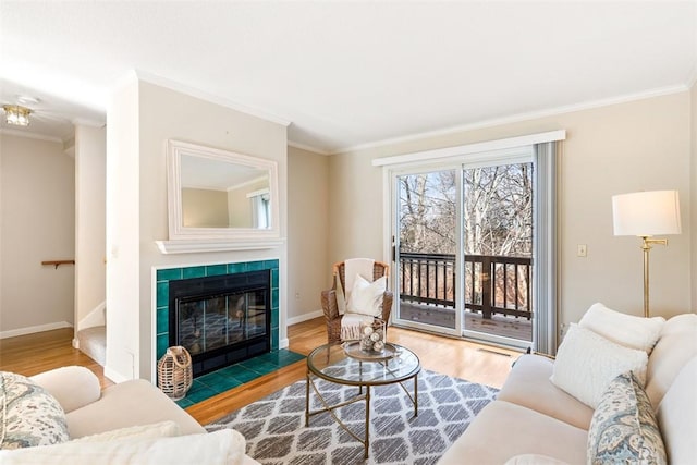 living room featuring hardwood / wood-style flooring, crown molding, and a tiled fireplace