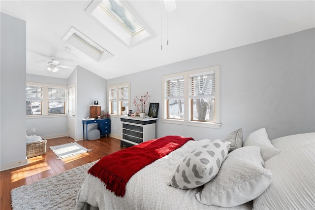 bedroom with lofted ceiling with skylight, ceiling fan, baseboards, and dark wood finished floors