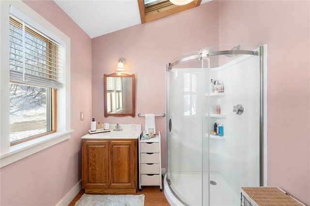 bathroom featuring wood finished floors, a shower stall, vanity, and baseboards