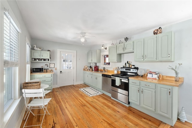 kitchen with appliances with stainless steel finishes, butcher block countertops, a sink, and light wood finished floors