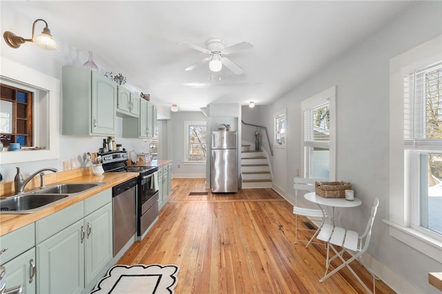 kitchen featuring light wood-style floors, butcher block counters, stainless steel appliances, and a sink