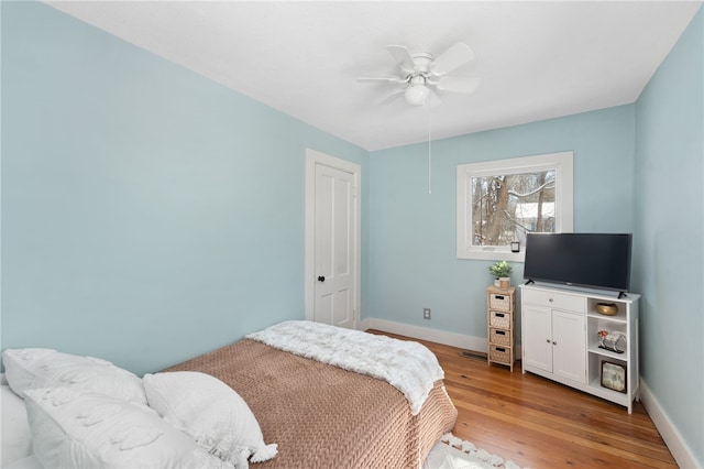 bedroom featuring a ceiling fan, baseboards, and light wood finished floors