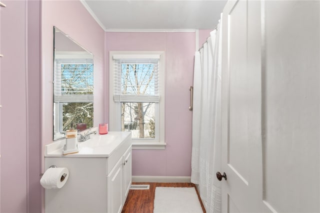 bathroom with baseboards, visible vents, ornamental molding, wood finished floors, and vanity