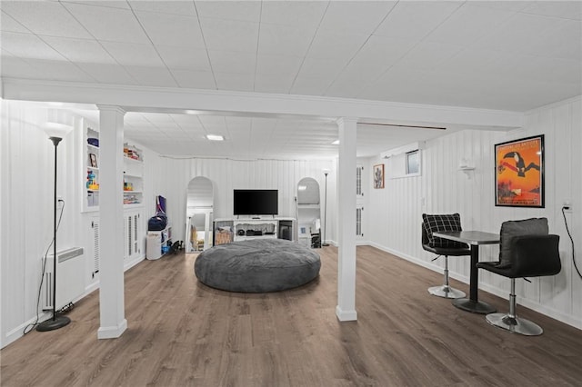 living area with arched walkways, baseboards, and wood finished floors