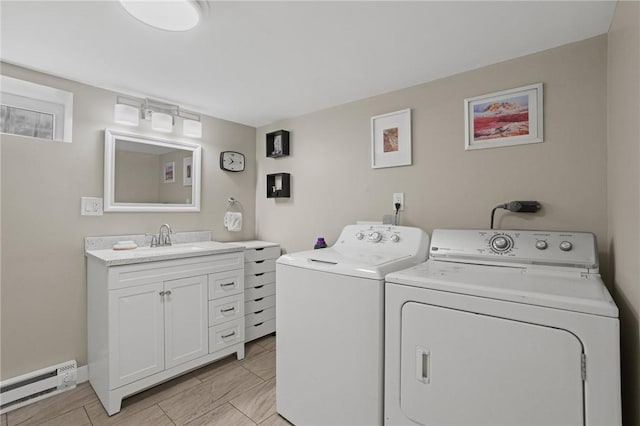 clothes washing area featuring a sink, a baseboard radiator, washing machine and dryer, and laundry area