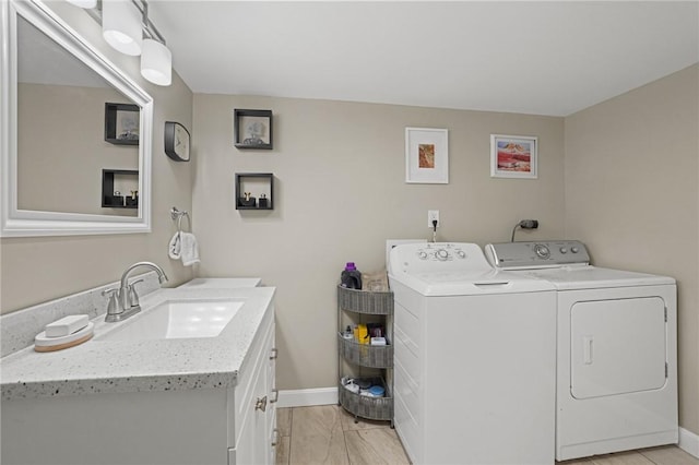 laundry area featuring washer and clothes dryer, baseboards, and a sink