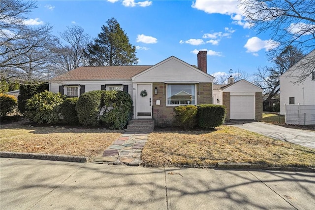 view of front of home featuring an outbuilding, a chimney, concrete driveway, and a garage