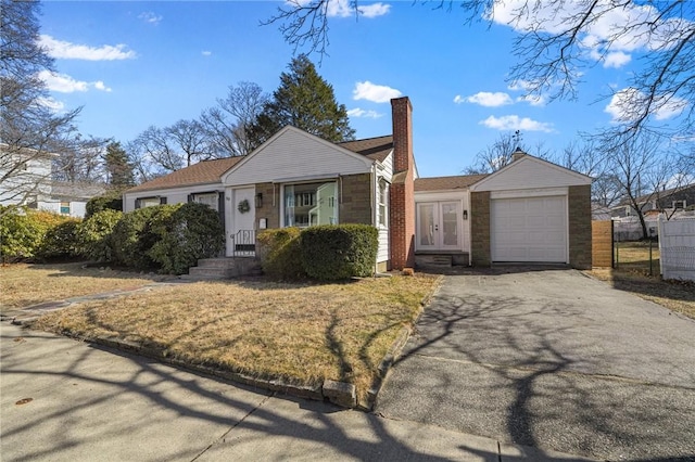 view of front of house with driveway, fence, french doors, a garage, and a chimney