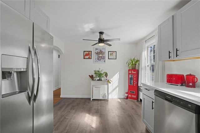 kitchen featuring ceiling fan, light countertops, appliances with stainless steel finishes, arched walkways, and dark wood-style flooring