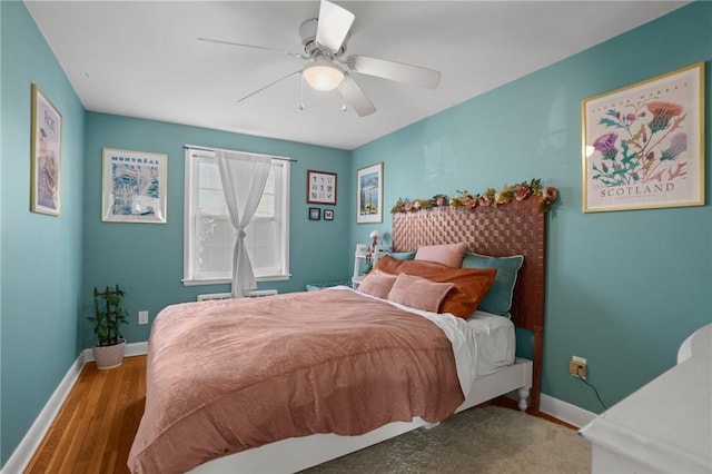 bedroom with ceiling fan, baseboards, and wood finished floors