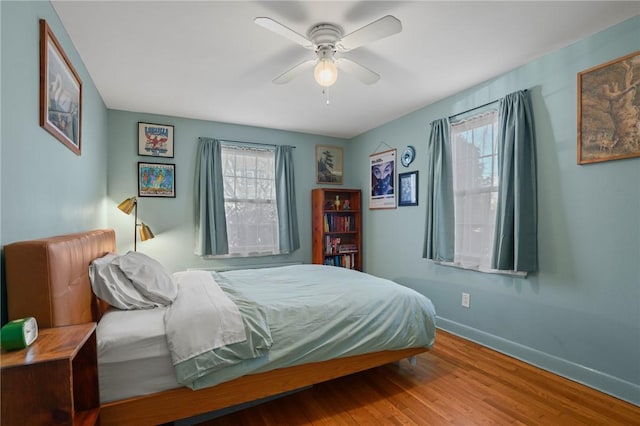 bedroom featuring baseboards, wood finished floors, and a ceiling fan