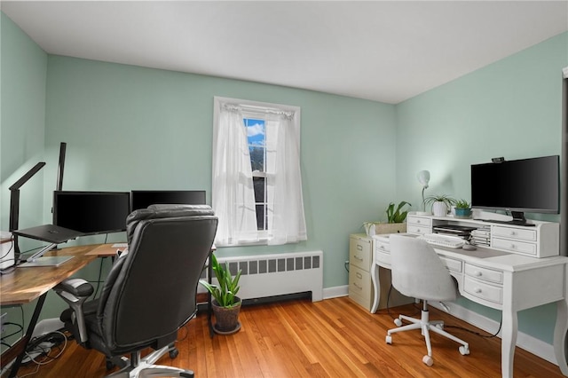 office space featuring light wood-type flooring, radiator heating unit, and baseboards