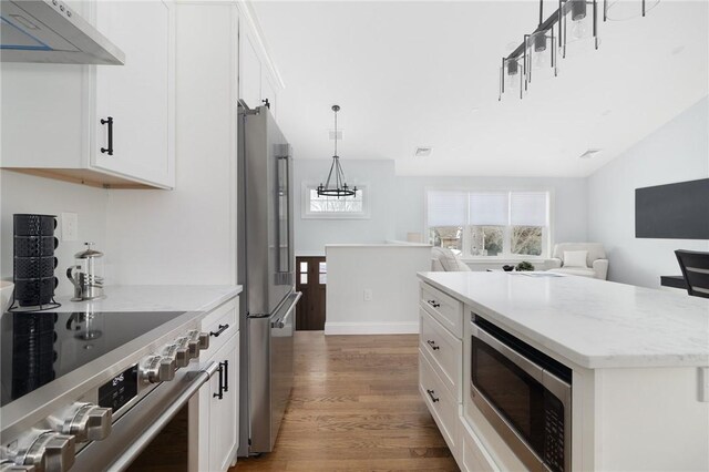 kitchen with a healthy amount of sunlight, white cabinets, wall chimney exhaust hood, and appliances with stainless steel finishes