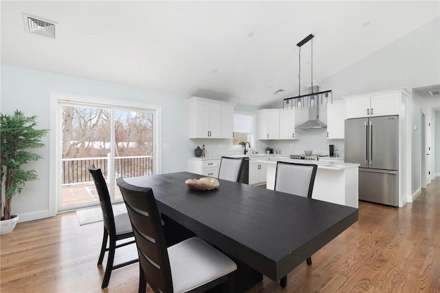 dining room featuring lofted ceiling, sink, and light wood-type flooring