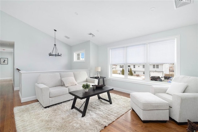 living room featuring hardwood / wood-style flooring, lofted ceiling, and a chandelier