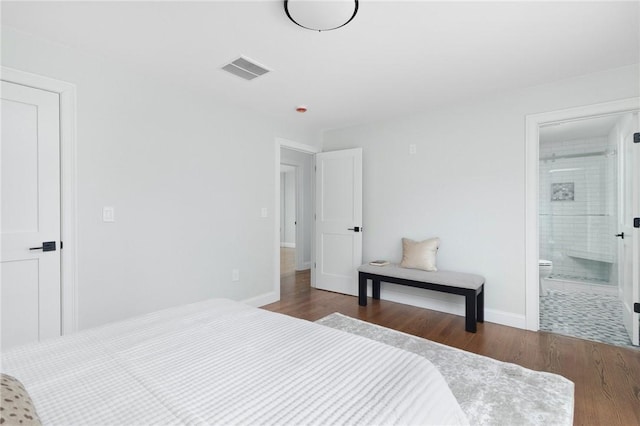 bedroom featuring ensuite bath and dark wood-type flooring