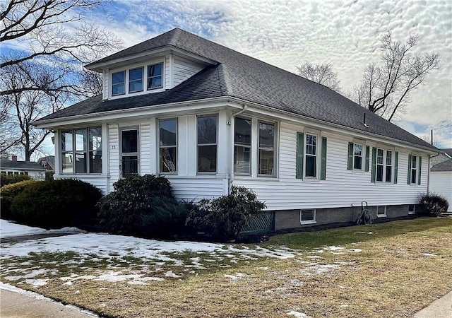 snow covered property with roof with shingles