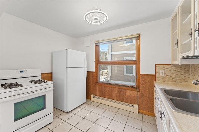 kitchen with white appliances, baseboard heating, sink, and wood walls