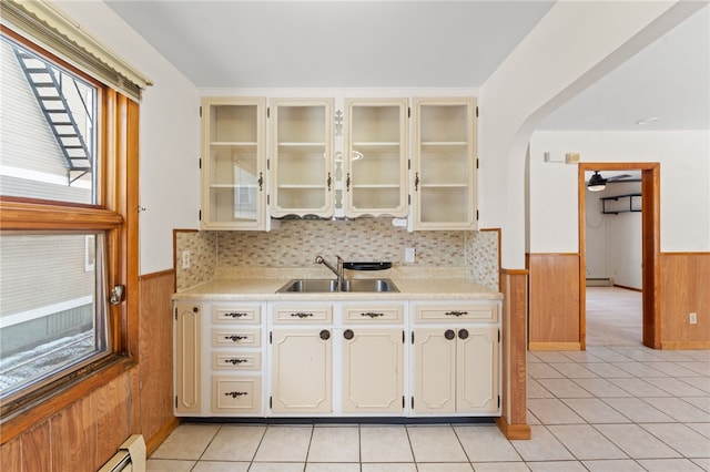 kitchen featuring light tile patterned flooring, ceiling fan, wooden walls, and sink