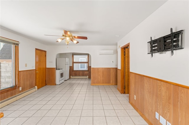 interior space with baseboard heating, ceiling fan, wood walls, and a wall unit AC