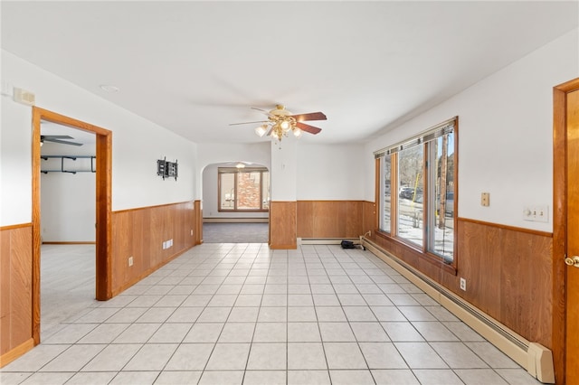 unfurnished room with a healthy amount of sunlight, light tile patterned floors, and wood walls