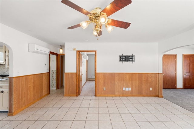 unfurnished room featuring a wall unit AC, light carpet, wooden walls, and ceiling fan