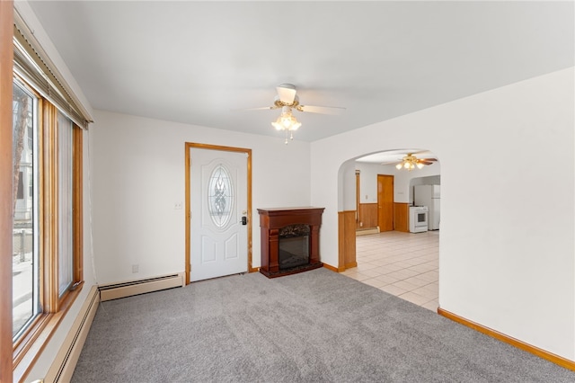 unfurnished living room featuring a baseboard heating unit, light carpet, and ceiling fan