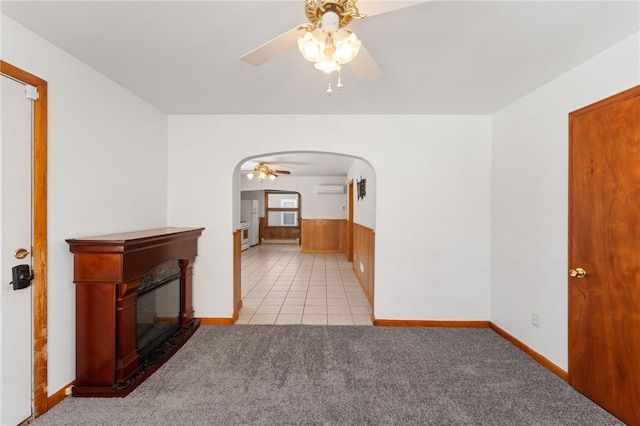 unfurnished living room featuring ceiling fan, a wall mounted AC, and light colored carpet