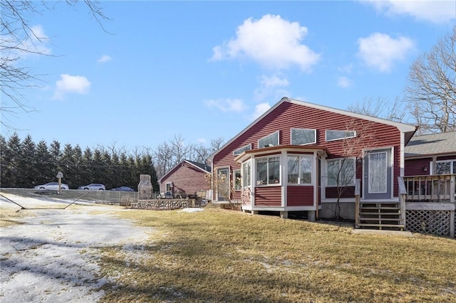 view of front of home featuring a sunroom, a deck, and a front yard