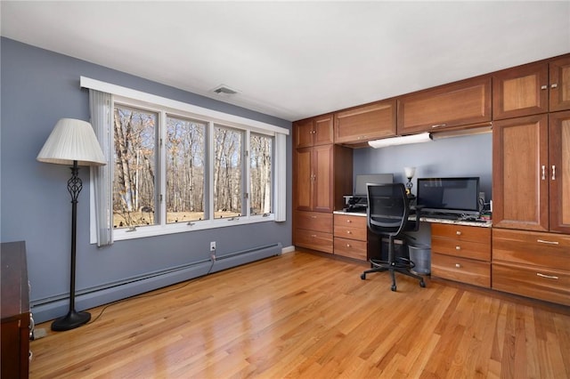 unfurnished office with a baseboard radiator, visible vents, and light wood-style flooring