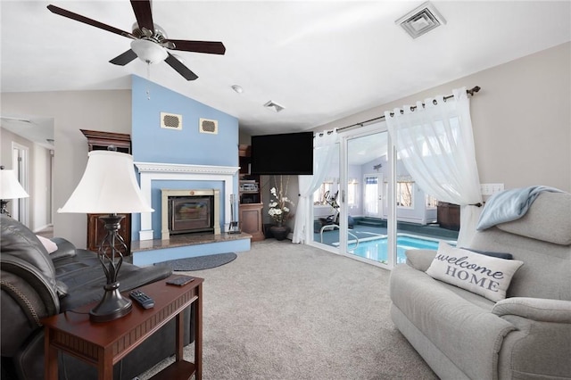 carpeted living room with visible vents, vaulted ceiling, and a glass covered fireplace