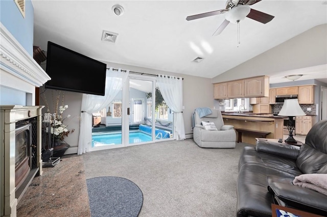 carpeted living area featuring vaulted ceiling, ceiling fan, a glass covered fireplace, and visible vents