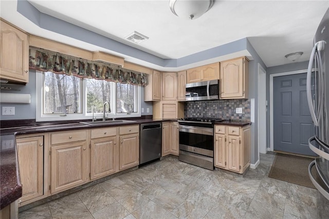 kitchen featuring light brown cabinets, a sink, visible vents, appliances with stainless steel finishes, and dark countertops