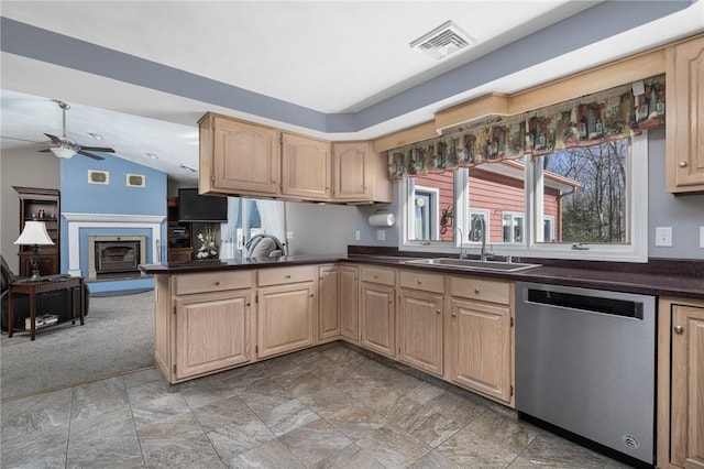 kitchen with stainless steel dishwasher, dark countertops, a sink, and visible vents