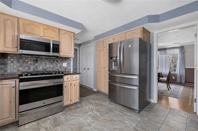 kitchen featuring stainless steel appliances, dark countertops, light brown cabinets, and backsplash