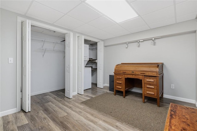 bedroom featuring baseboards, a drop ceiling, wood finished floors, and multiple closets